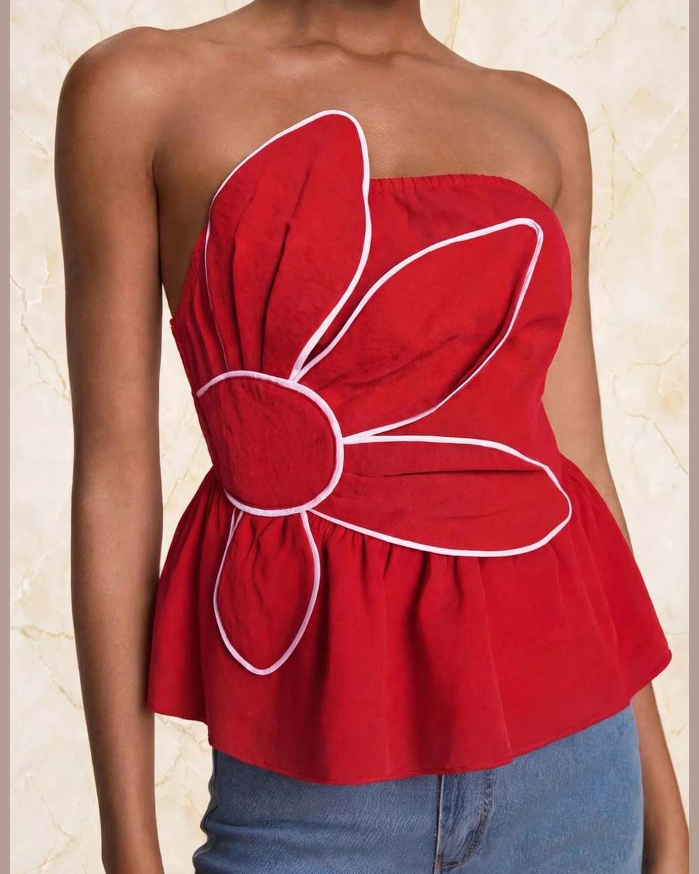 Modelo con blusa roja strapless con flor 3D y ribete blanco