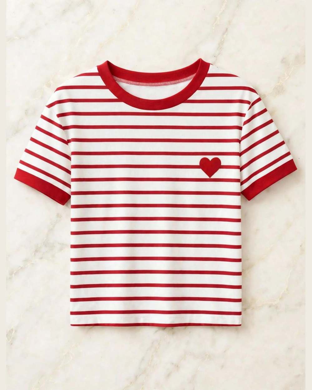 Blusa de rayas rojo/blanco con corazón rojo bordado, aislada (gancho, mano y gráfico con texto eliminados) sobre mármol marfil