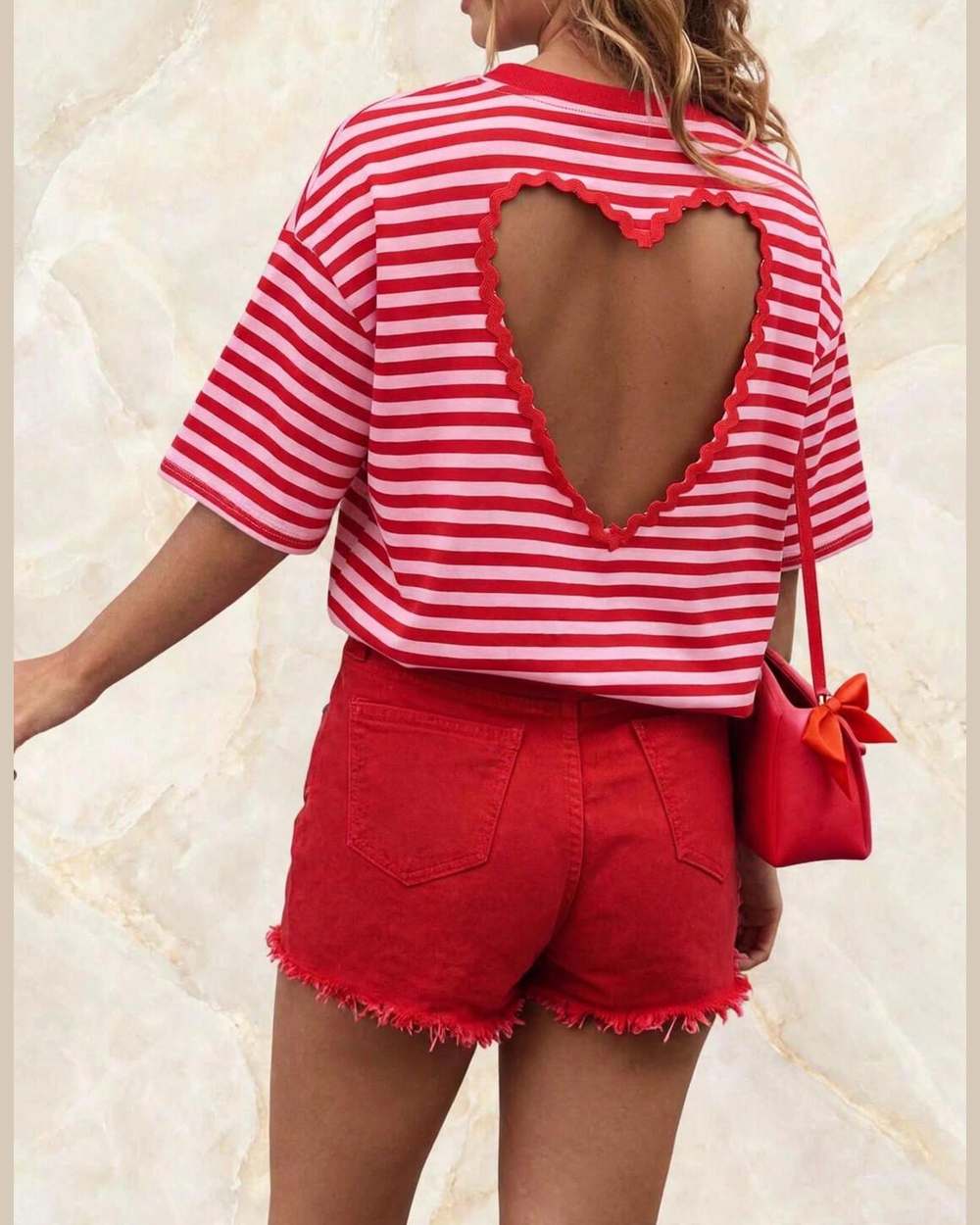 Modelo vista desde atrás con blusa de rayas rojo/rosa y recorte de corazón en la espalda