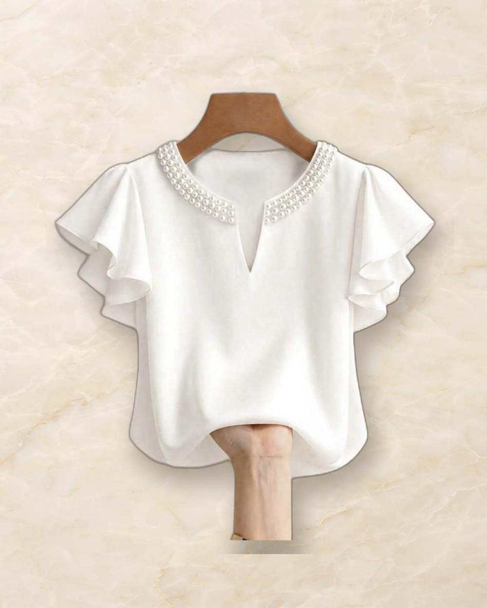 Blusa blanca con cuello bordado de perlas y mangas con volado., aislado sobre mármol marfil