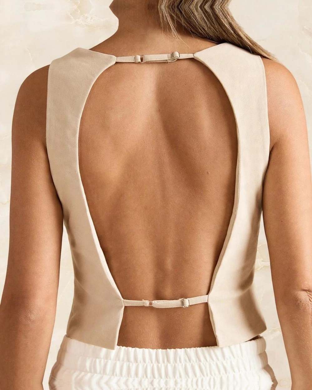 Blusa beige espalda abierta, aislado sobre mármol marfil