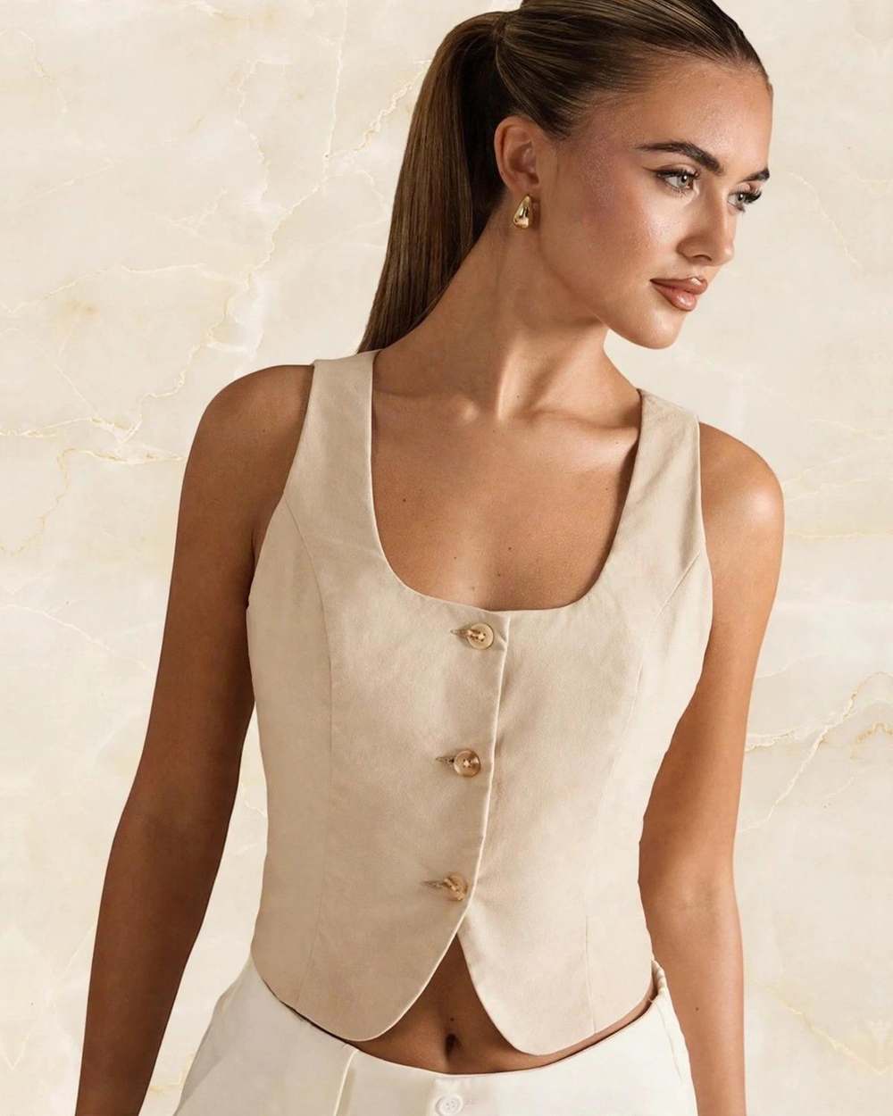 Blusa beige botones frente, aislado sobre mármol marfil