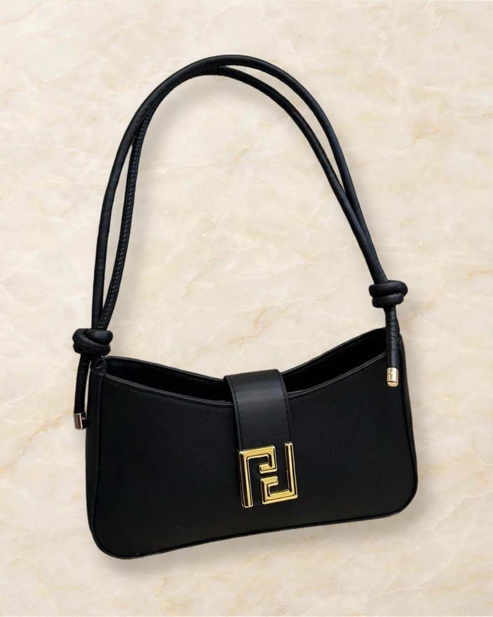 Cartera negra de hombro con broche dorado estilo F., aislado sobre mármol marfil