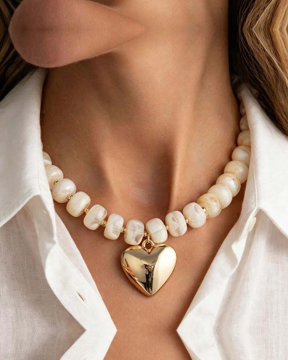 Collar perlas barrocas corazon dorado, aislado sobre mármol marfil