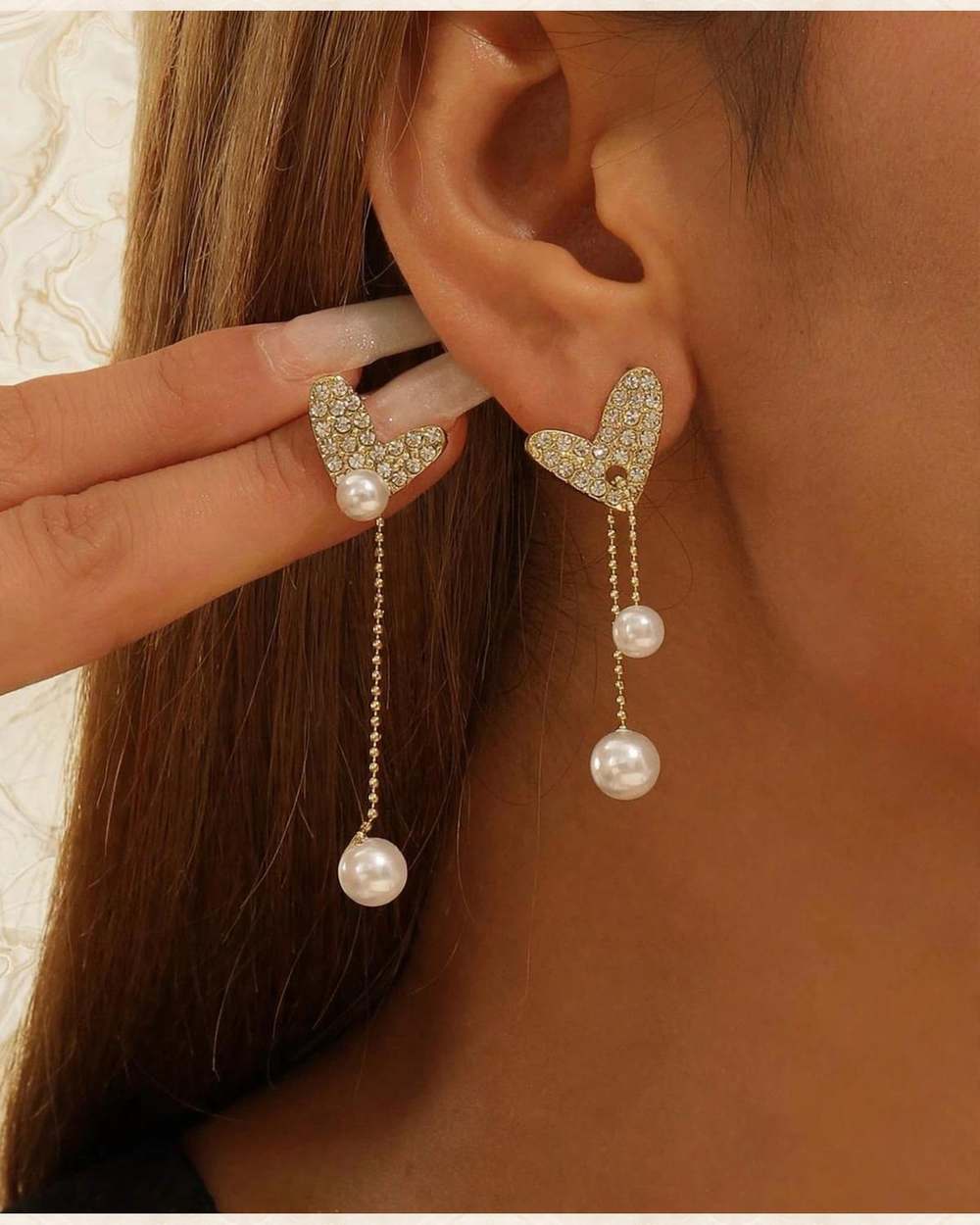 Zarcillos de corazon con perla blanca., aislado sobre mármol marfil