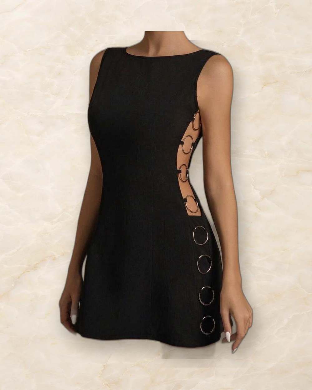 Vestido negro con recortes laterales y aros metalicos., aislado sobre mármol marfil